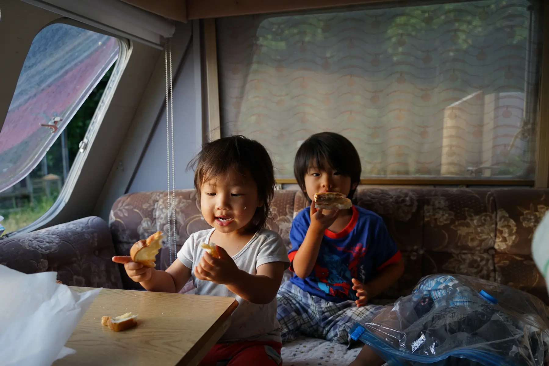 Two children sharing food inside a caravan