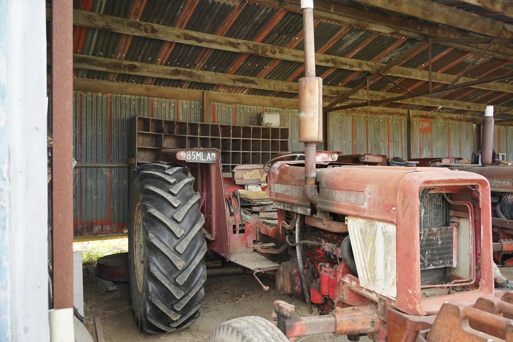 A weathered red tractor in a farm shed