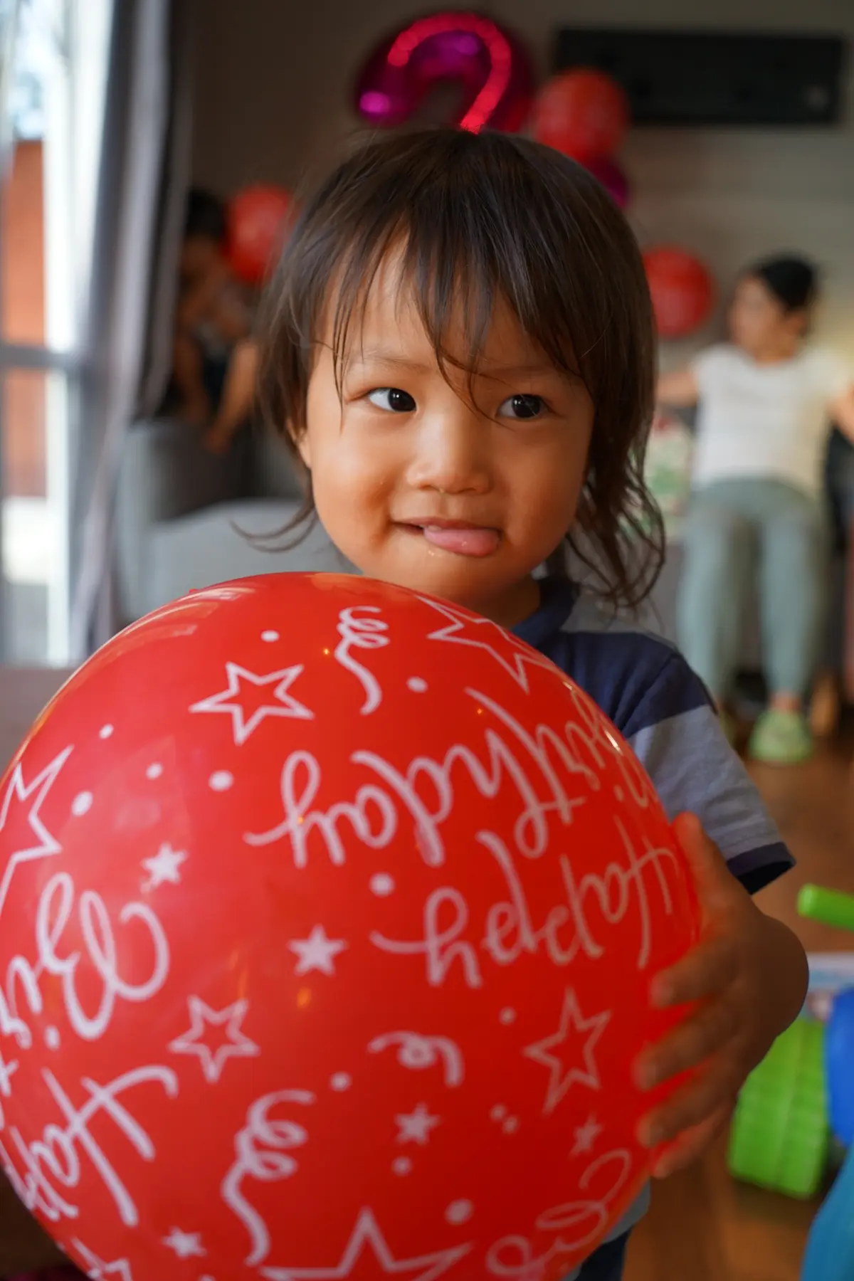 A smiling child holding a red balloon